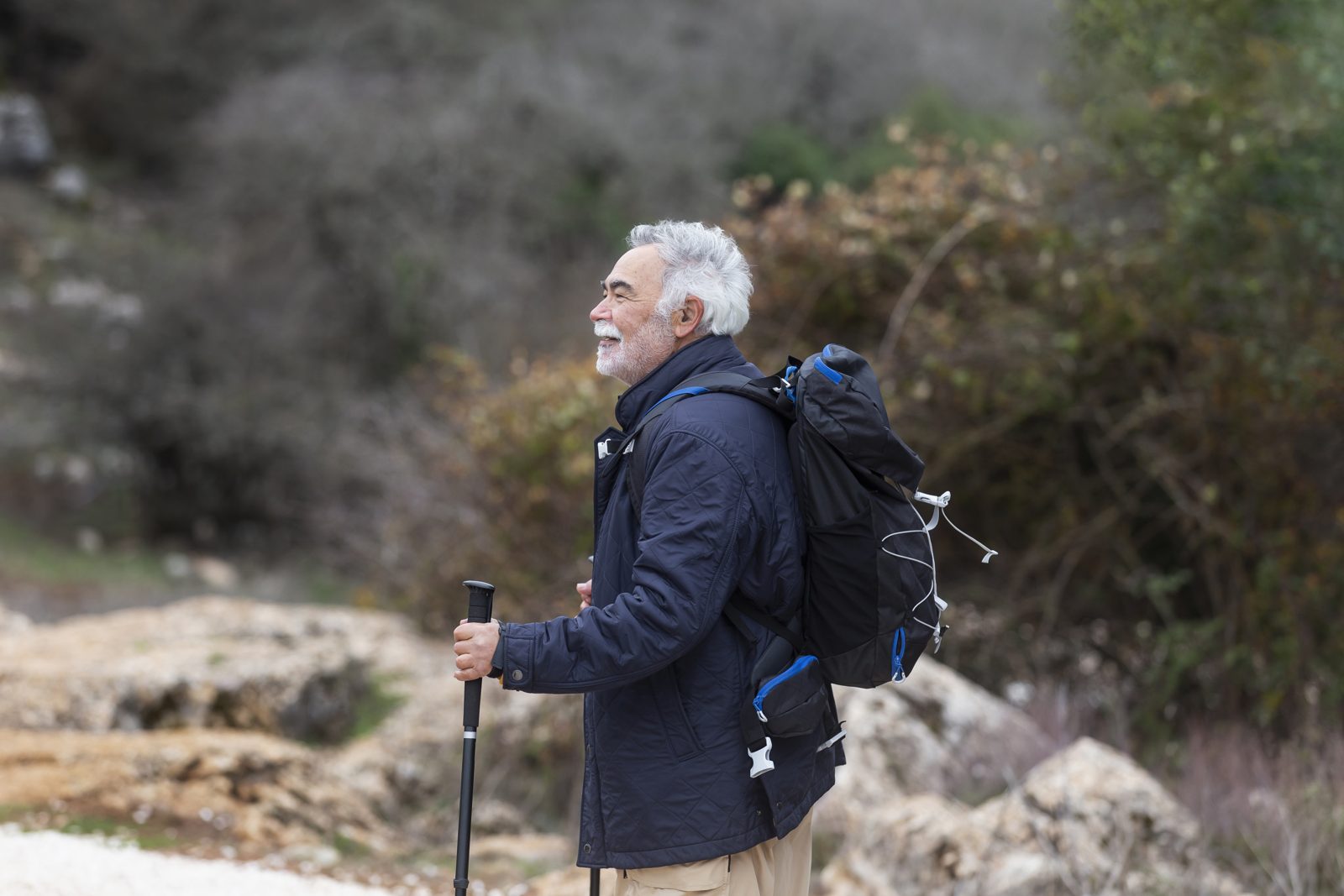 A man hiking a rocky mountain trail, looking out over the view.
